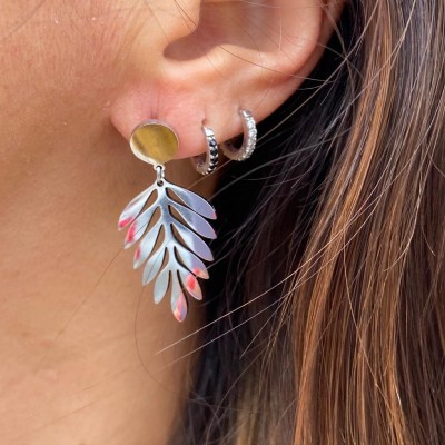 Brincos dourado e prateado em orelha com cabelo castanho