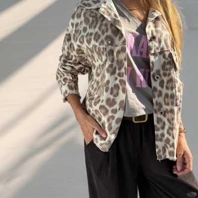 Casaco animal print bege e castanho com botões, t-shirt cinza com texto rosa, calças pretas largas e acessórios dourados