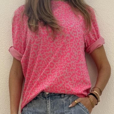 Pessoa com t-shirt rosa de padrão animal print e calças de ganga azul claro.