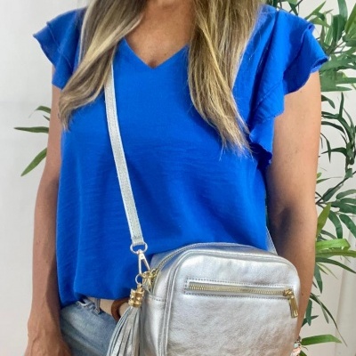 Mulher com bolsa prateada pequena e blusa azul