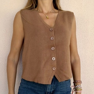 Colete de malha castanho claro com botões frontais usados com calças de ganga azuis