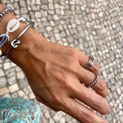 Mão feminina com anéis e pulseiras sobre calçada portuguesa