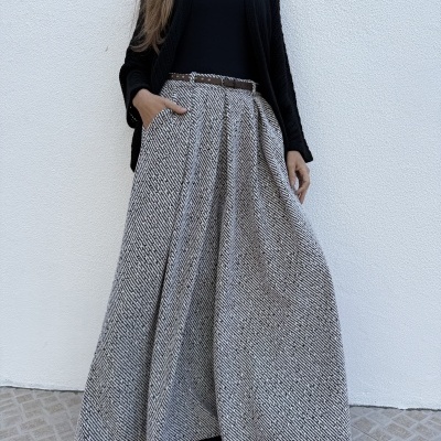 Saia comprida preta e branca com padrão geométrico, cinto castanho, top preto e cardigan preto