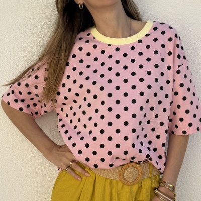 T-shirt rosa com bolinhas pretas e gola amarela, calças amarelas com cinto bege e acessórios dourados