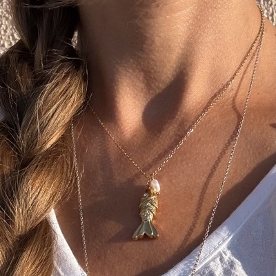 Colar dourado com pendente de peixe e pérola ao pescoço