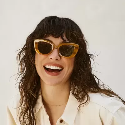 Mulher a usar óculos de sol amarelos com lentes escuras e camisa clara