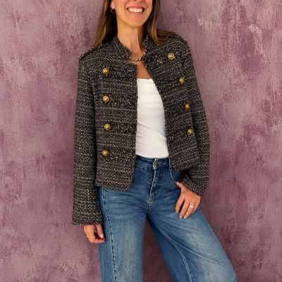 Blazer tweed preto com botões dourados, t-shirt branca e jeans azuis, parede lilás texturizada