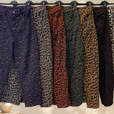 Calças com padrão animal print em diferentes cores penduradas em cabides