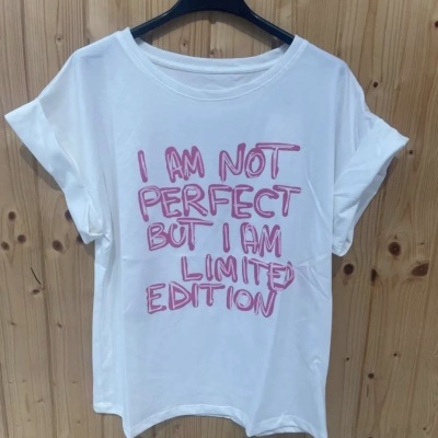 T-shirt branca com texto rosa pendurada num cabide contra fundo de madeira