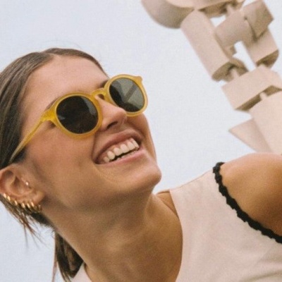 Mulher sorridente a usar óculos de sol amarelos com fundo neutro