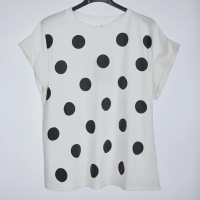 T-shirt branca com bolinhas pretas e mangas curtas num cabide