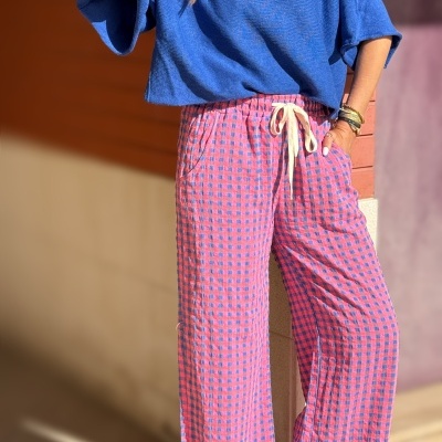Mulher a usar camisola azul e calças xadrez rosa e azul ao ar livre