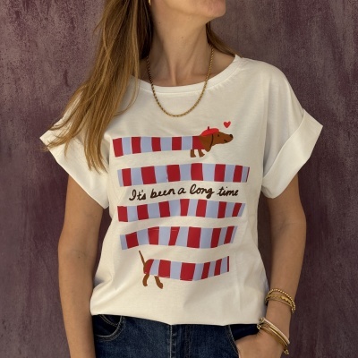 T-shirt branca com estampa de cão castanho com boina vermelha e riscas vermelhas e azuis e texto Its been a long time