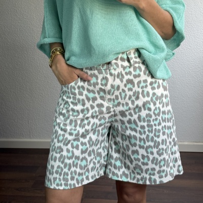 Pessoa com camisola de malha verde água e calções com padrão de leopardo em verde e cinzento.