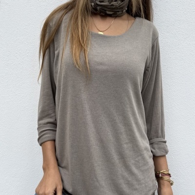 Pessoa com camisola castanha, lenço camuflado e calças de ganga