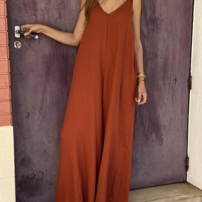 Macacão largo laranja em mulher junto a porta roxa com maçaneta metálica