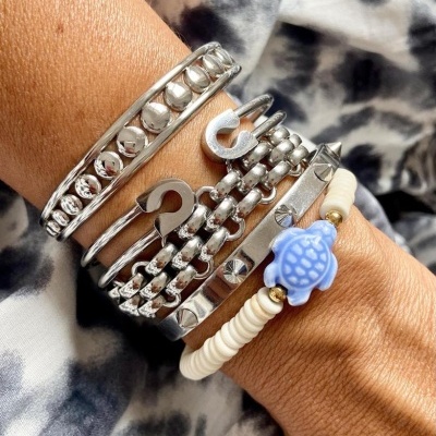 Pulseiras metálicas e de contas com pendente de tartaruga azul no pulso