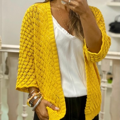 Casaco amarelo de malha texturizada usado com blusa branca e calças pretas