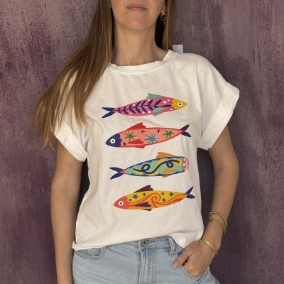 T-shirt branca com estampado de peixes coloridos, usada por mulher com calças de ganga azul claro.
