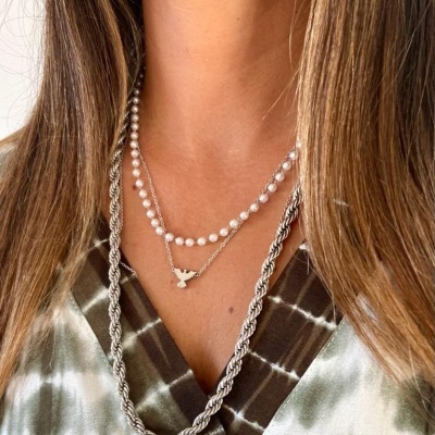 Colar de pérolas e corrente com pendente de pá usado por mulher