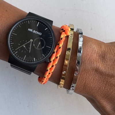 Relógio preto MR. BOHO com pulseiras laranja, dourada e prateada no pulso