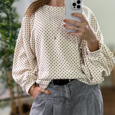 Camisola bege com corações pretos e calças de ganga cinza.