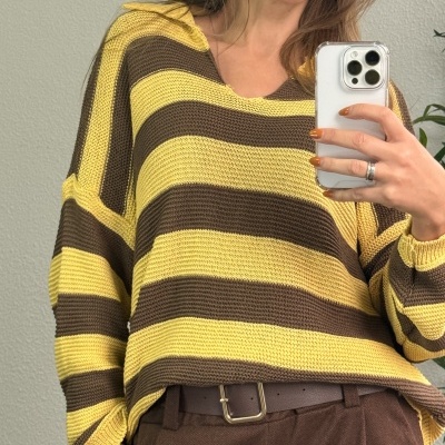 Camisola às riscas amarelas e castanhas com capuz, usada com calças castanhas e cinto castanho.