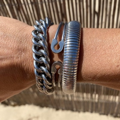 Três pulseiras prateadas em metal num braço