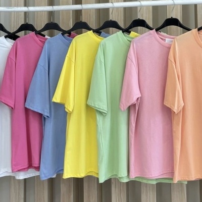 Sete t-shirts coloridas de manga curta em cabides suspensos.