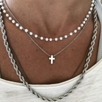 Colares de pérolas e prata com pendente de cruz sobre camisa branca