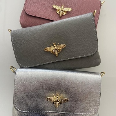 Três malas pequenas em pele com abelhas douradas no fecho, em rosa, cinza e prateado