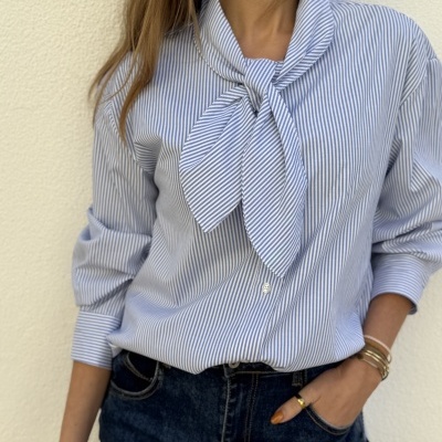 Camisa de riscas azuis e brancas com laço e calças de ganga azuis