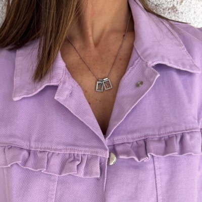 Colar prateado com três pendentes retangulares brilhantes numa camisa lilás com folhos