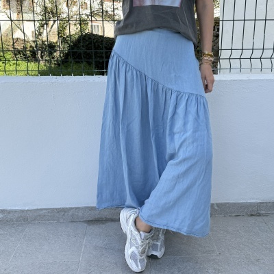 Saia azul clara assimétrica com pregas, t-shirt cinza escuro e ténis brancos