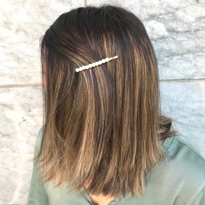 Presilha de cabelo com pérolas brancas em cabelo castanho claro com madeixas