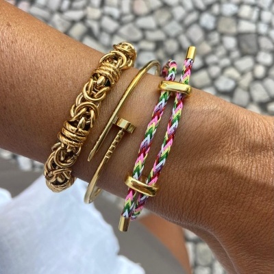 Três pulseiras no pulso em fundo de calçada portuguesa