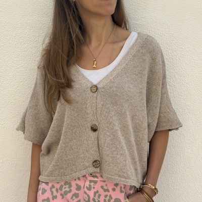 Mulher a usar cardigan bege com botões de madeira e calças rosa com padrão animal