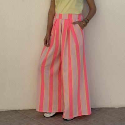 calças largas riscas rosa e amarelas com cintura alta e bolsos, t-shirt amarela, pulseiras douradas e ténis brancos