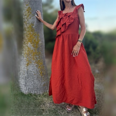 Vestido longo vermelho com folhos usado ao ar livre próximo a uma árvore