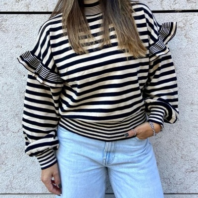 Top de riscas pretas e bege com folhos em mulher com calças de ganga claras
