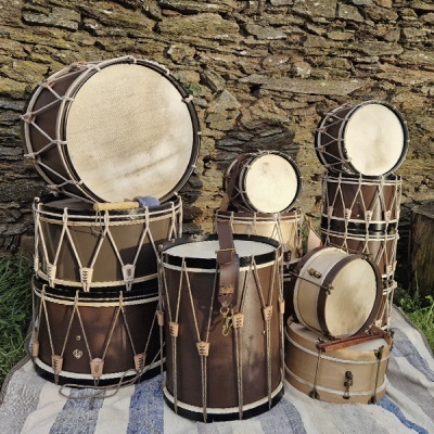 Conjunto de tambores de pele e madeira com cordas em exterior sobre manta riscada