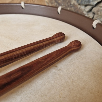 Baqueta de madeira sobre pele de tambor clara com aro castanho