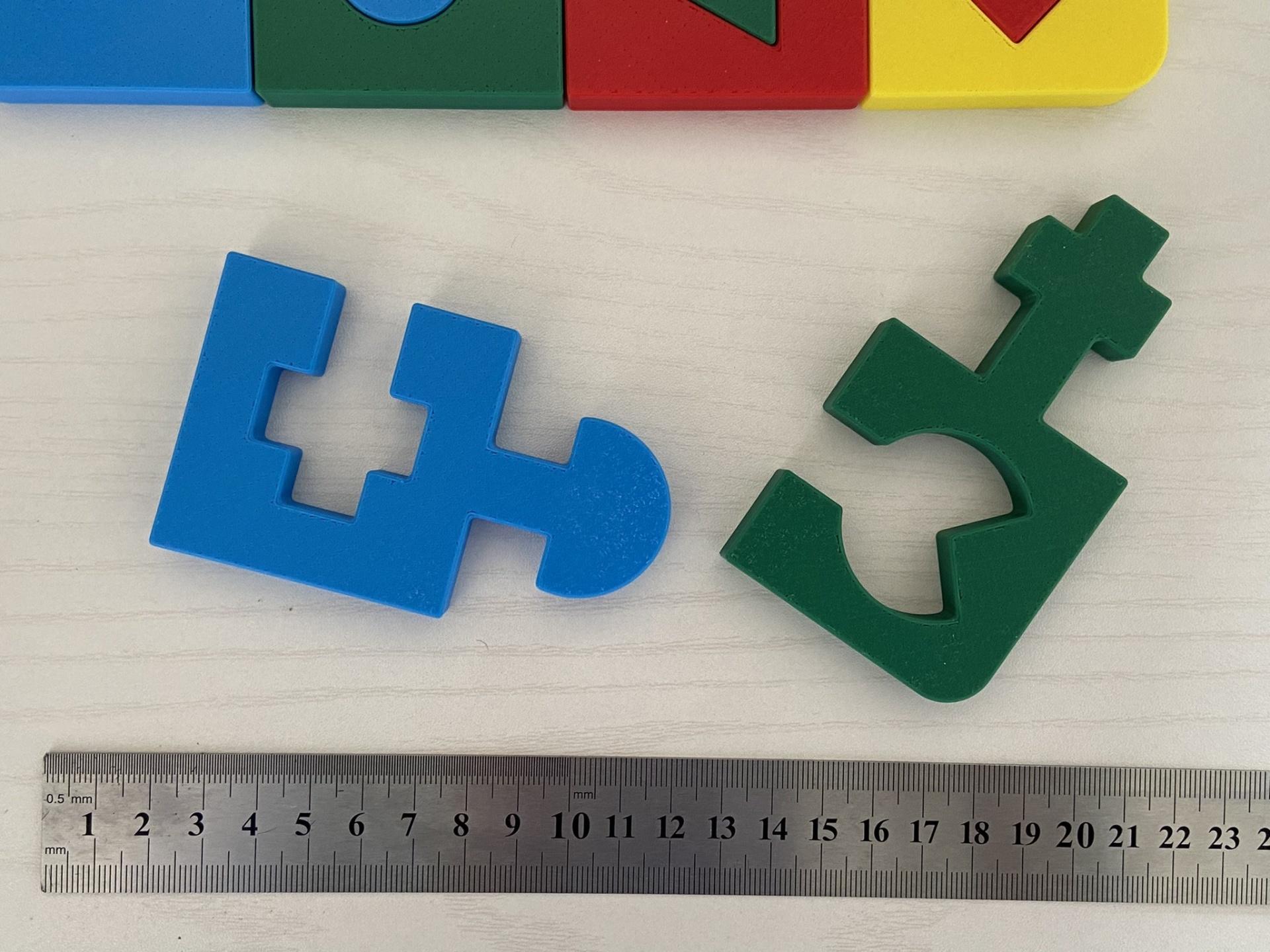 Puzzle educativo # 4 cores Peças de encaixe azul e verde com régua metálica sobre superfície clara