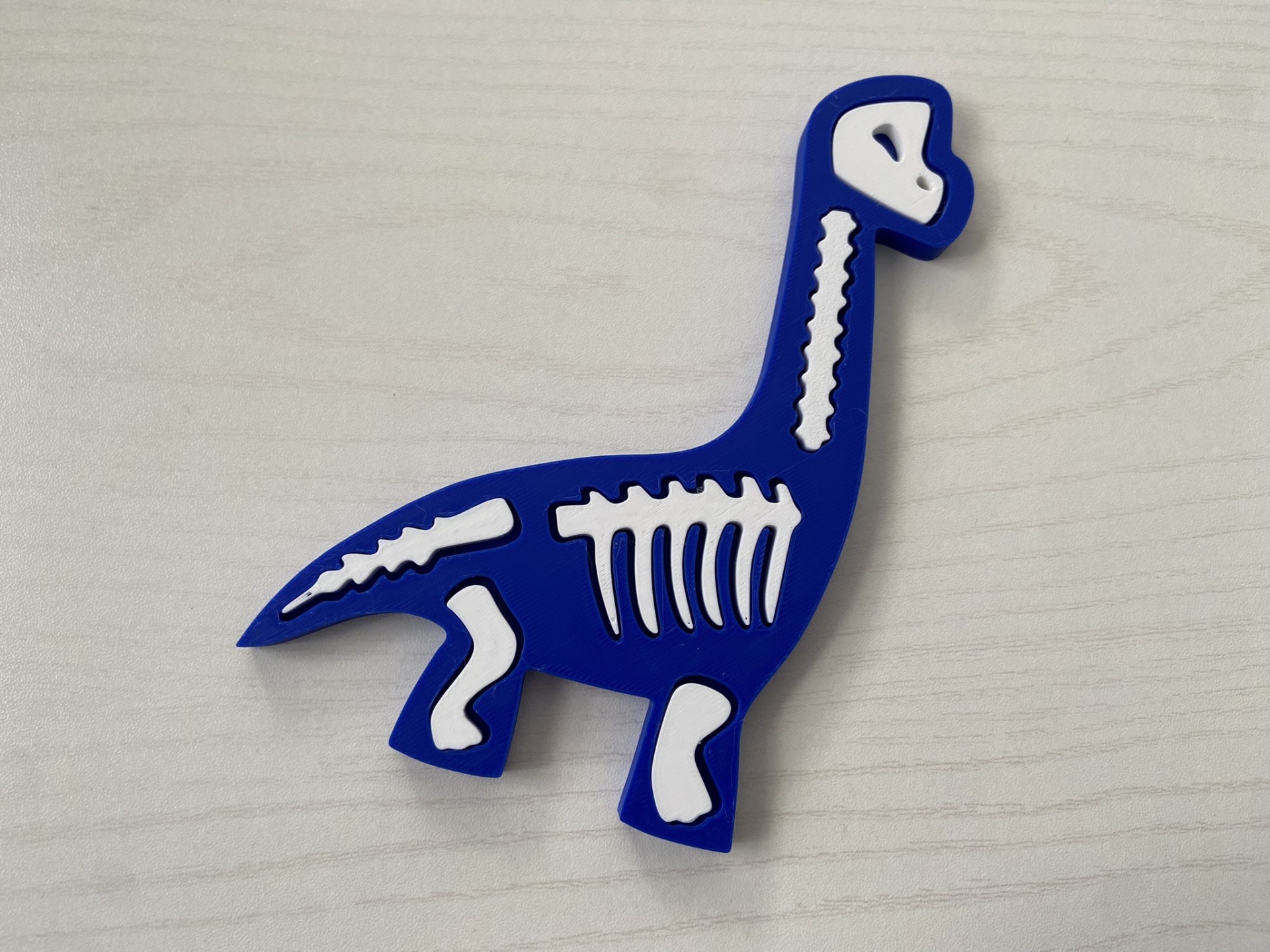 Puzzle # Dinossauros # Kit 2 Brinquedo dinossauro azul com ossos brancos sobre superfície clara