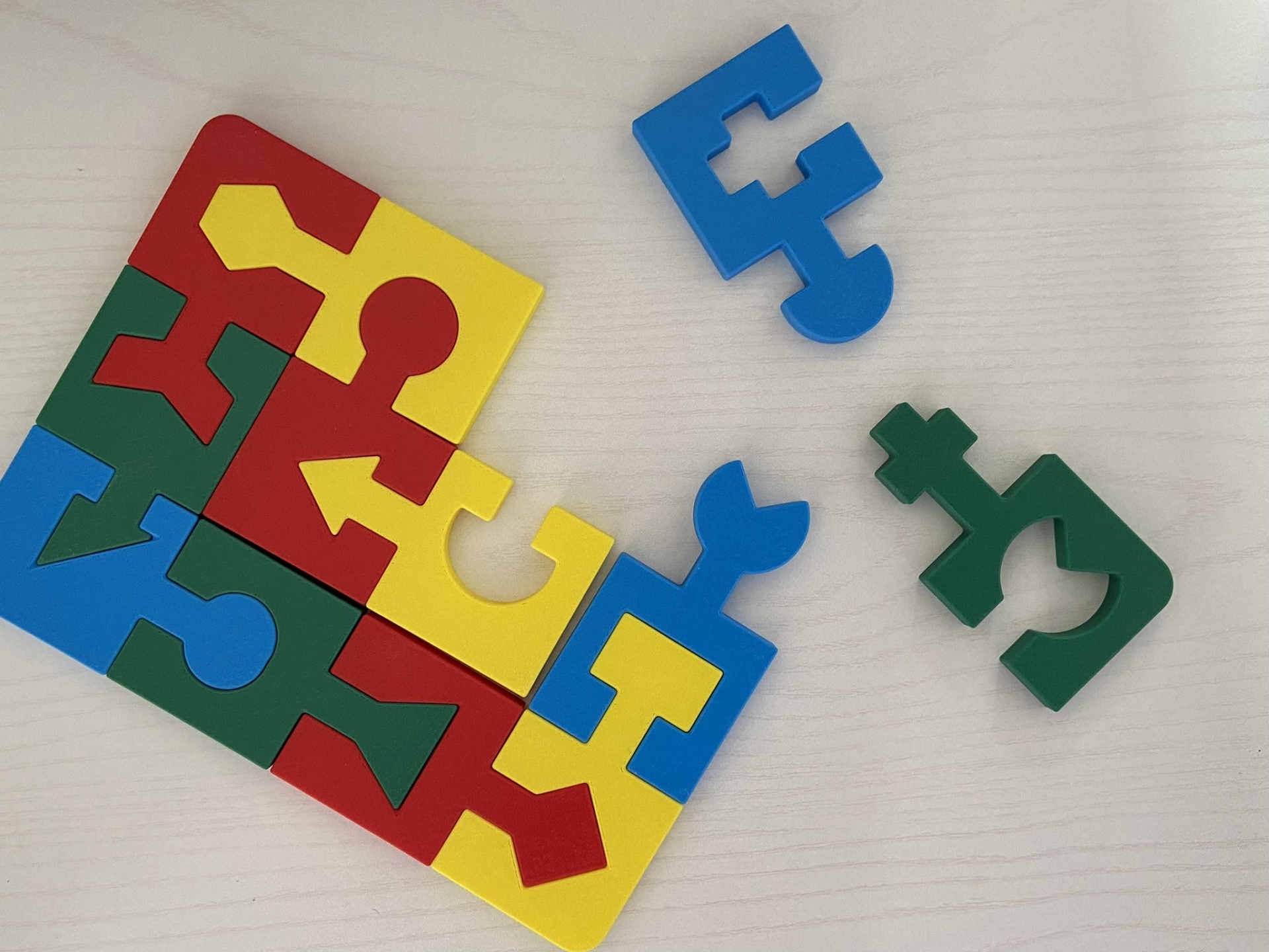 Puzzle educativo # 4 cores Peças coloridas de puzzle em plástico parcialmente montadas sobre uma mesa clara