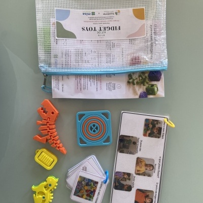 Kit de Fidget Toys com brinquedos coloridos e cartões em bolsa zip de rede.
