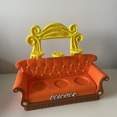 Miniatura de sofá em plástico laranja e amarelo com texto FR!E.N.D.S