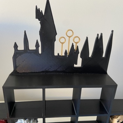 Estante preta com silhueta do castelo de Hogwarts e varinhas de magia
