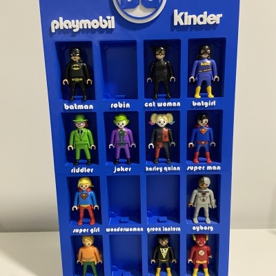 Conjunto de bonecos Playmobil de personagens DC em placa azul com logotipos playmobil, DC e Kinder.