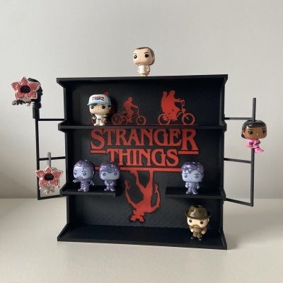 Display preto com figuras Funko Pop da série Stranger Things e texto STRANGER THINGS vermelho